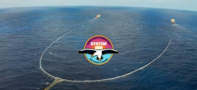 Ocean and horizon with long view of Ocean Cleanup’s System 002 with its two vessels, long net, and retention zone.